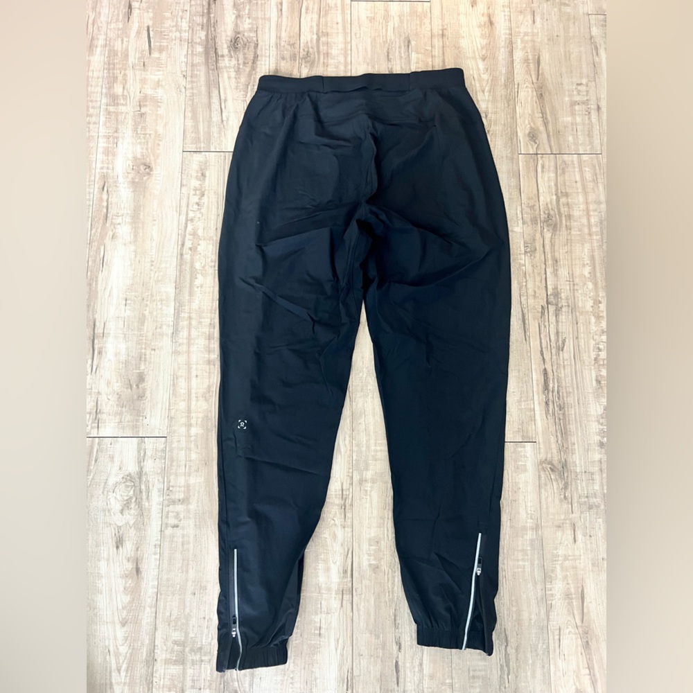 Lululemon Men's Black Pace Breaker Pants with ankle zips and zipper pockets.